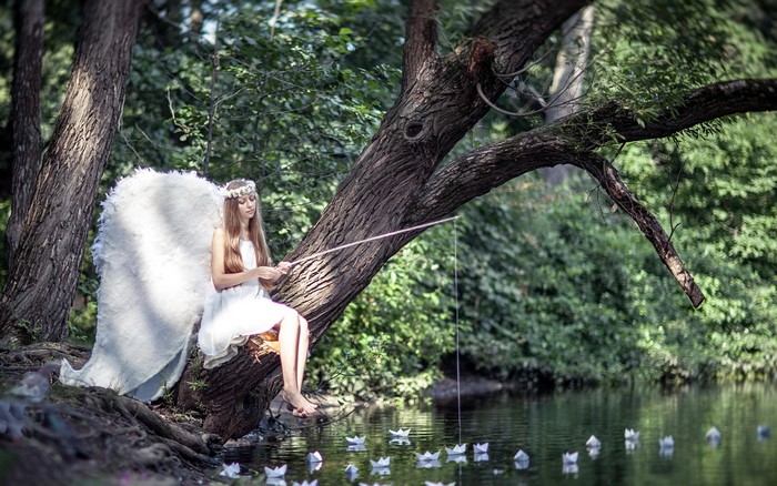 Angel fishing paper boats from a tree