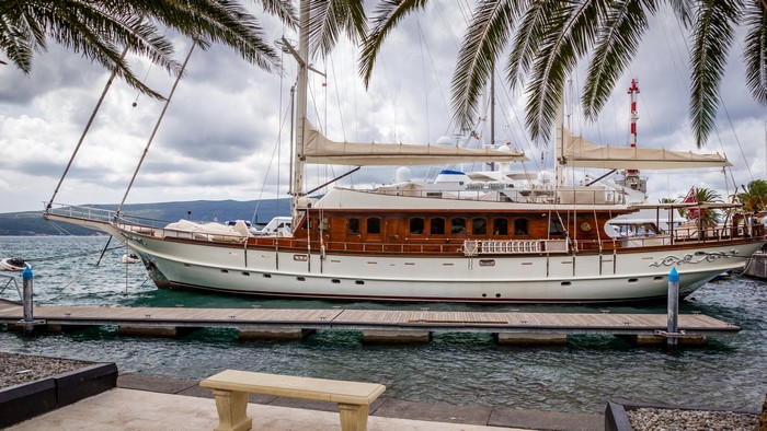 Sailing yacht docked at a marina with palm trees