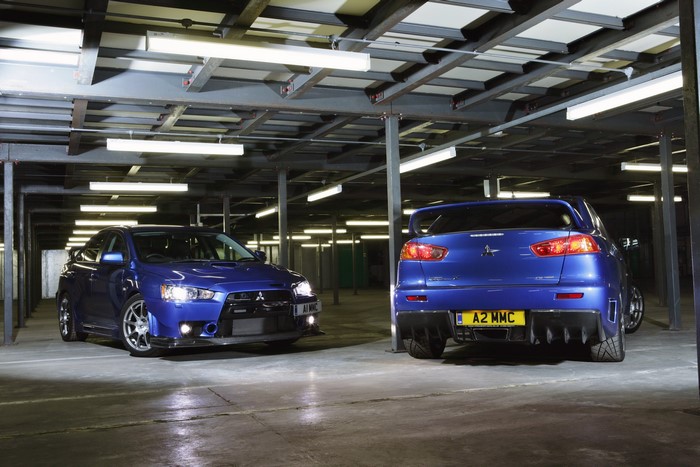Two blue Mitsubishi Lancer Evolution X FQ-400 cars in a parking garage