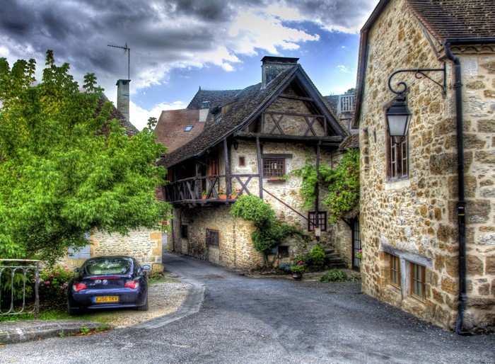 Street in a French village with stone houses and a car