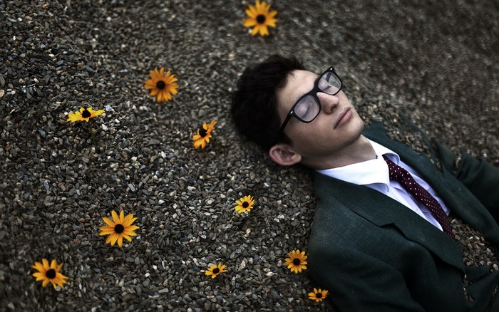 Man in Suit Sleeping Among Flowers and Stones