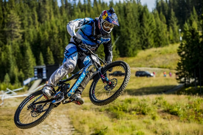 Man in Red Bull helmet riding a downhill mountain bike
