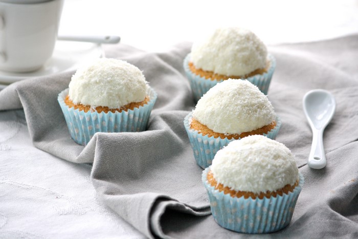 Four coconut cupcakes on a grey cloth