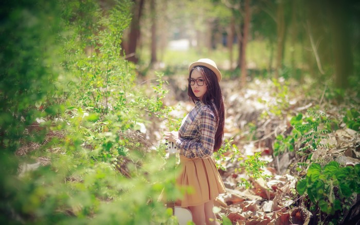 Asian girl with glasses and hat holding guitar