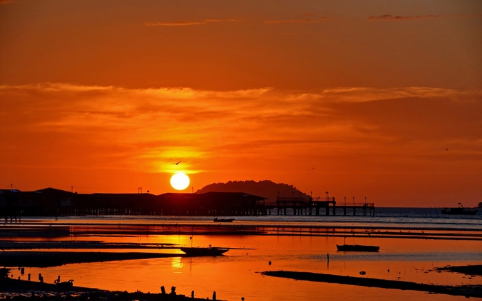 Sunset over a coastal town with a pier