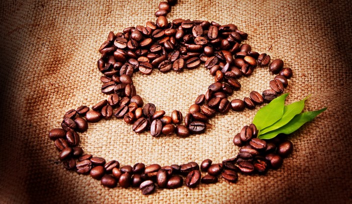 Coffee beans arranged in a heart shape with leaves