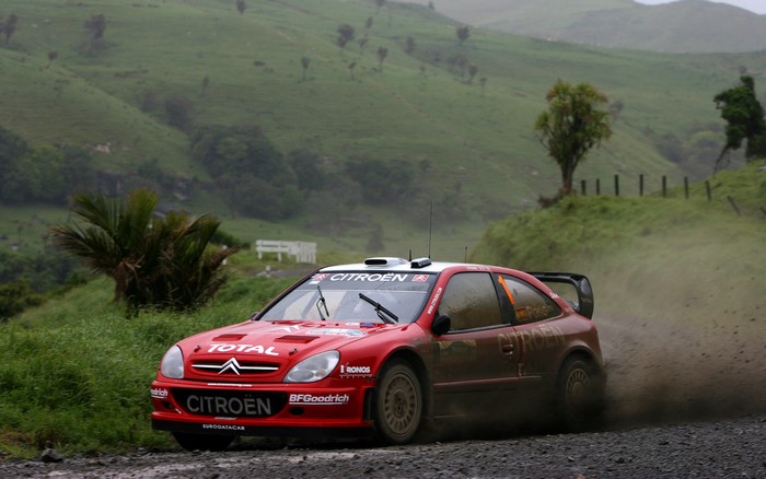 Red Citroen Xsara rally car driving on a dirt road