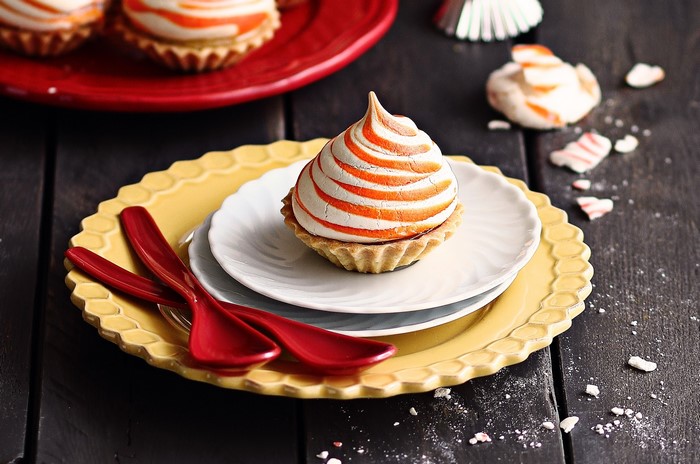 Orange and white swirled meringue tarts on plates