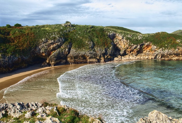 Beach cove with rocky cliffs and green hills in Asturias, Spain