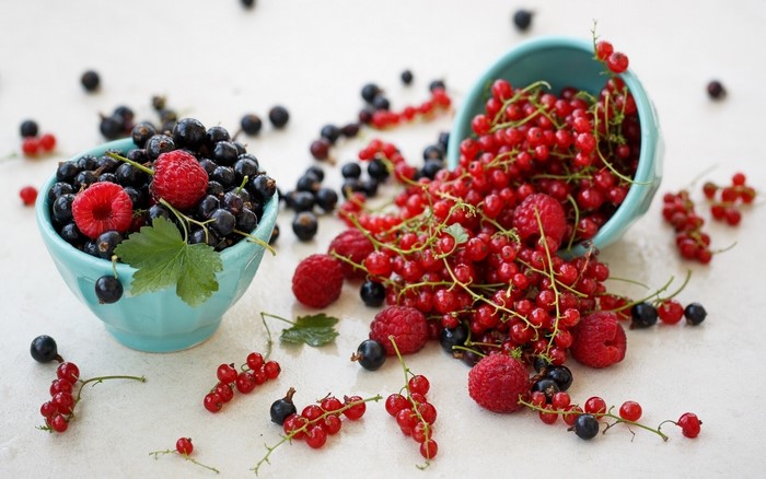 Blackcurrants and redcurrants with raspberries in bowls