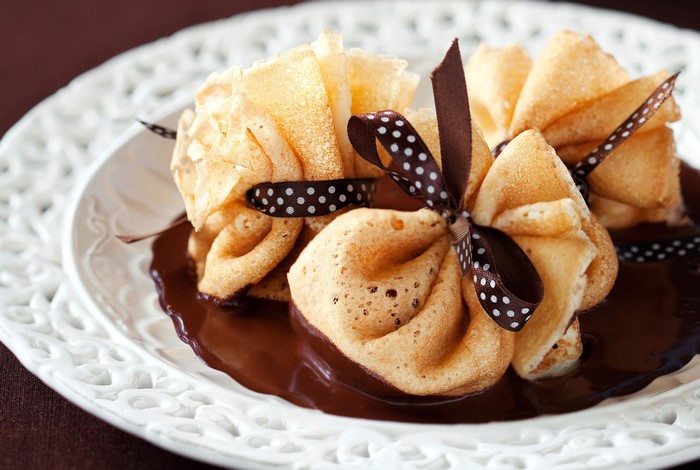 Dessert crepes tied with ribbon in chocolate sauce