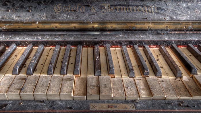 Close-up of an old, dusty piano with visible brand name
