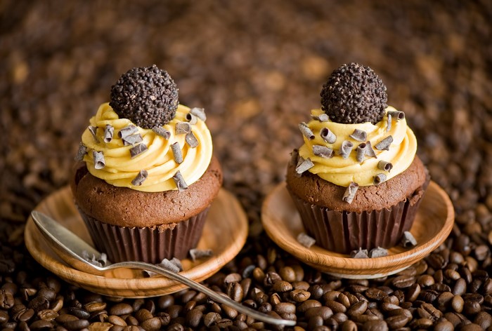 Two chocolate cupcakes with yellow frosting and chocolate shavings