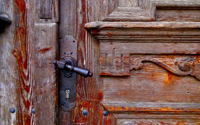 Closeup of an old wooden door with a metal handle and lock