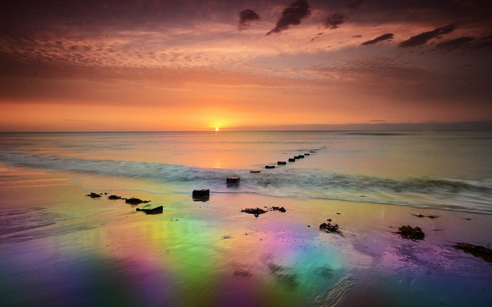 Rainbow beach at sunset with wooden posts