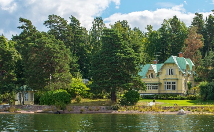 Yellow house with green roof by the water in Sweden
