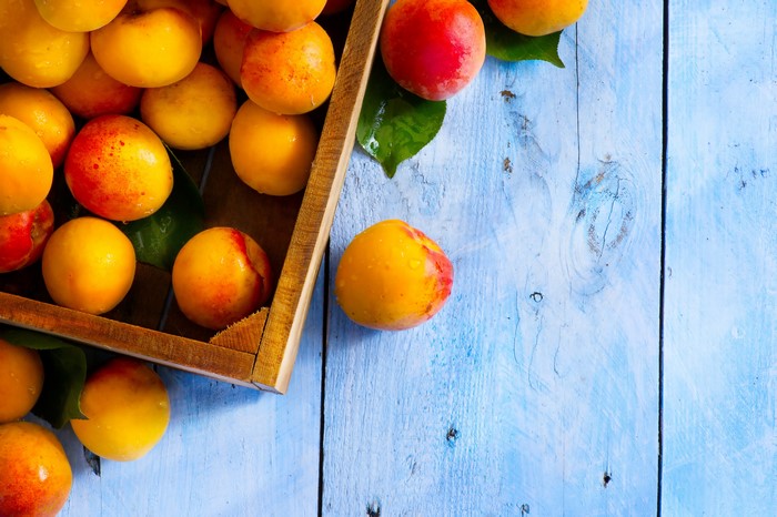 Apricots in a wooden crate on a blue table