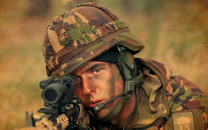 Soldier aiming a rifle with camouflage face paint