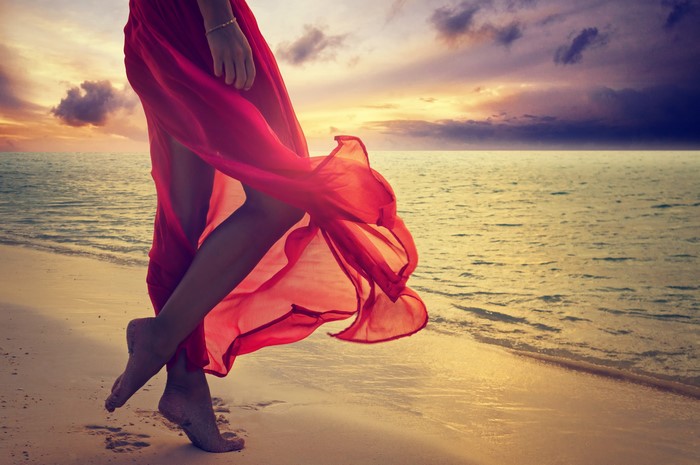 Woman in red dress on beach at sunset