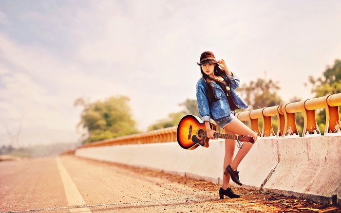 Asian woman with guitar on a road