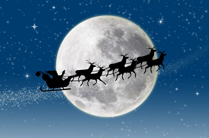 Santa Claus and reindeer flying in front of the moon