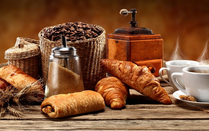 Coffee beans, pastries, and coffee cups on a wooden table