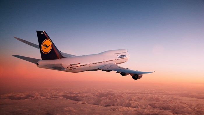 Lufthansa Boeing 747-8 flying above clouds at sunset