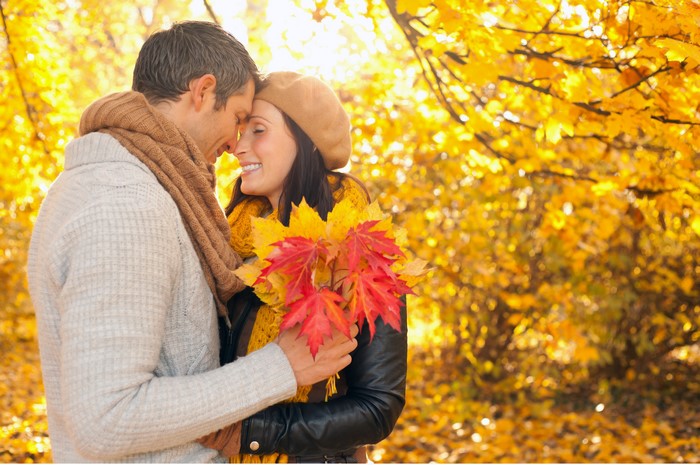 Couple in love holding maple leaves in autumn
