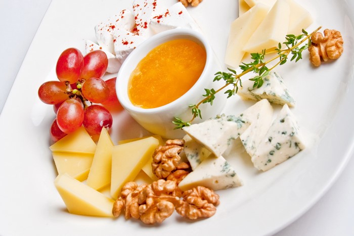 Cheese platter with grapes, honey, walnuts, and herbs