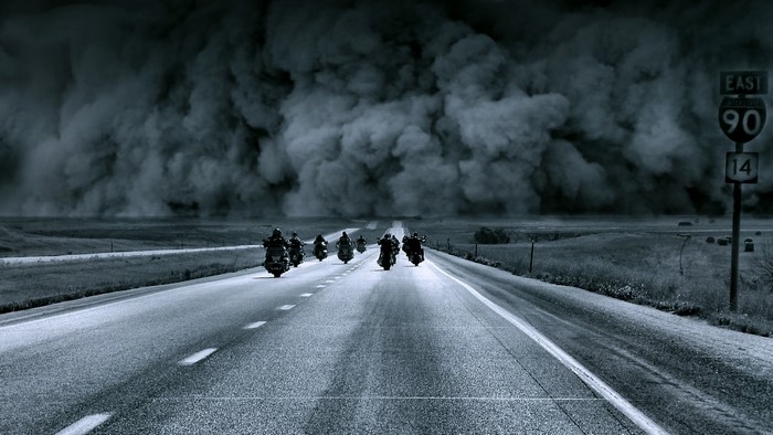 Motorcyclists riding on a road during a dust storm