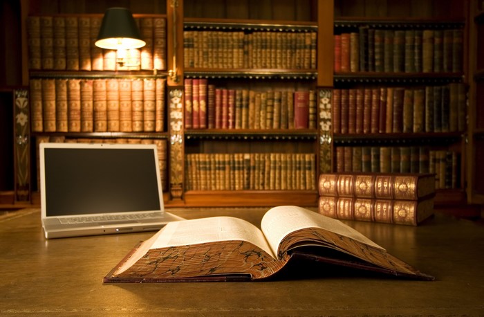 Laptop and open book in a library
