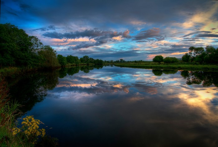 River reflecting colorful sunset clouds and trees