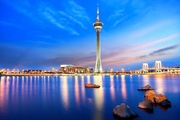 Macau Tower and bridge over water at dusk