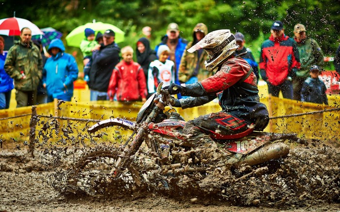 Motocross rider splashing through mud