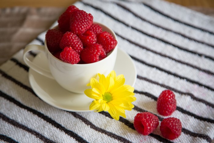 Raspberries in a cup with a yellow flower