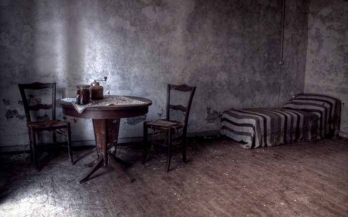 Abandoned room with table, chairs, and bed
