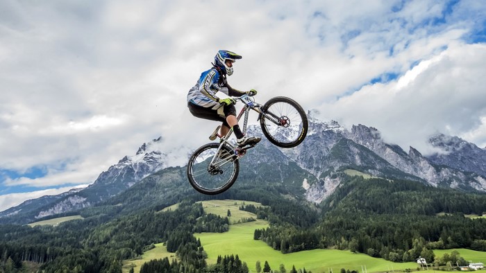 Mountain biker performing a jump with mountains in the background