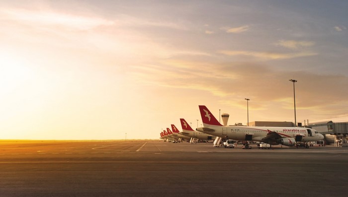 Air Arabia airplanes parked at an airport during sunset