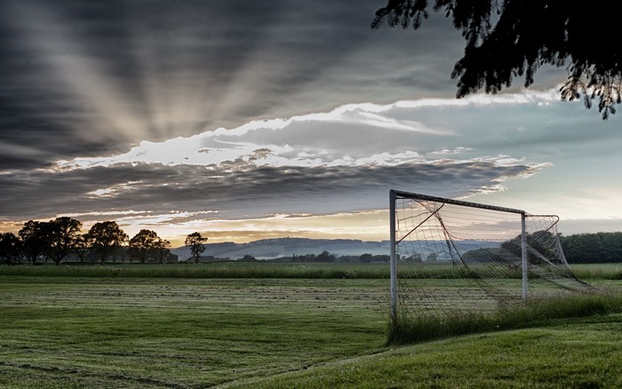 Soccer goal on a grassy field at sunrise
