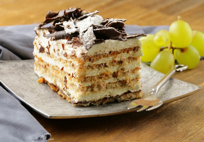 Slice of layered cake with chocolate shavings and grapes