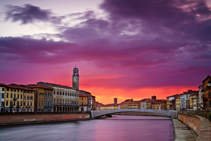 Pisa, Italy cityscape with river and bridge at sunset