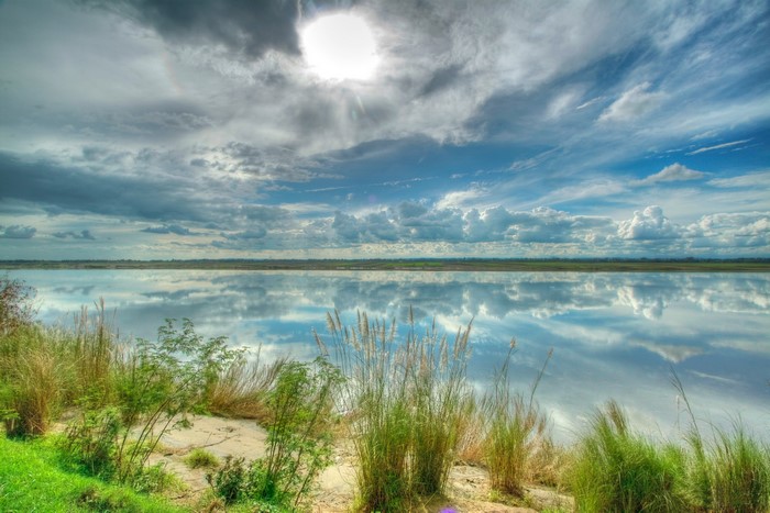River reflecting clouds and sky with grass on the bank