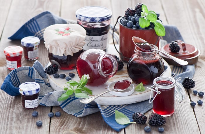 Jars of berry jam with fresh berries and spoons