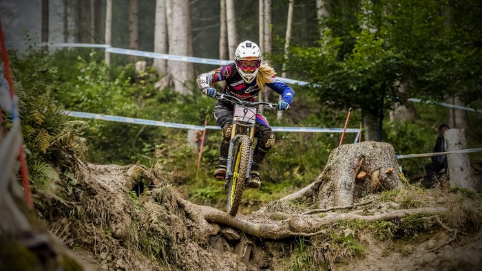 Woman downhill mountain biking on a muddy course