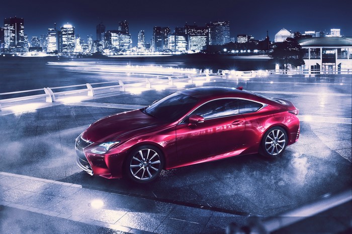 Red Lexus RC coupe parked at night with city skyline
