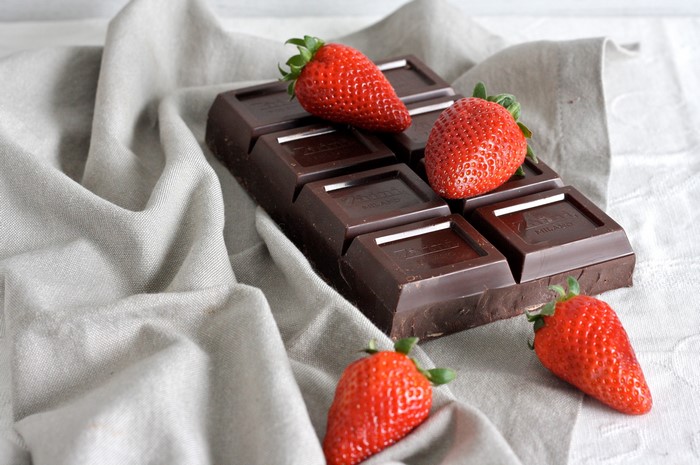 Dark chocolate bar with fresh strawberries on a linen cloth