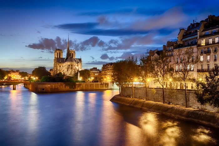 Notre Dame de Paris at night along the Seine River