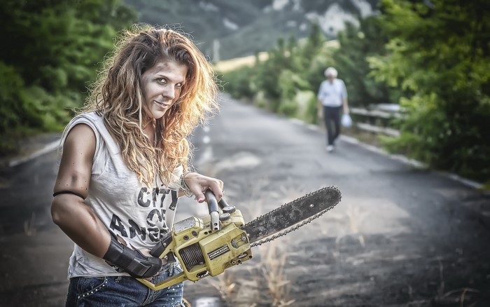 Woman with chainsaw on a road