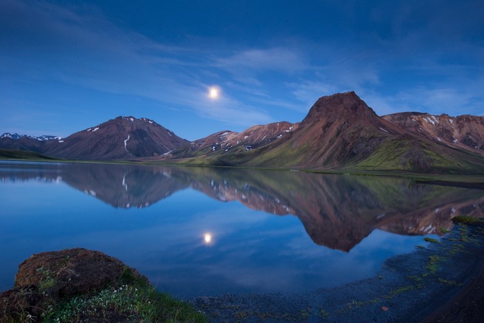 Mountains reflected in a lake in Iceland under the moon