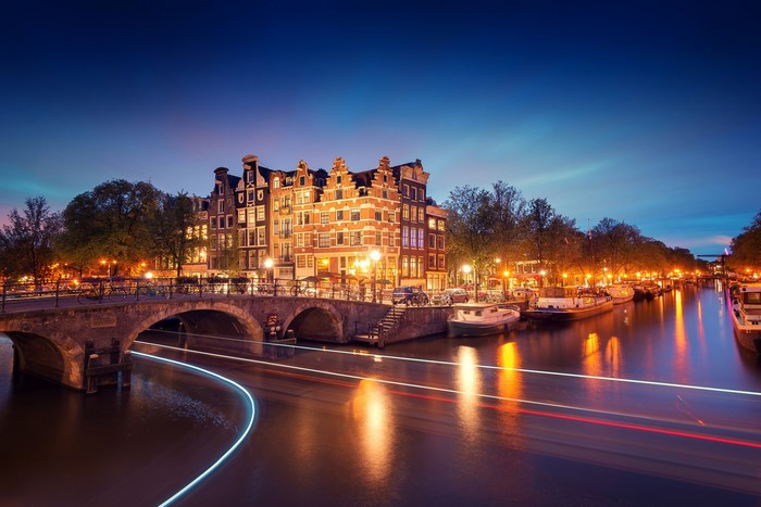 Amsterdam canal at night with bridge and boats